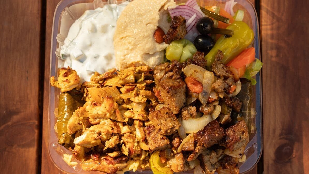 Chicken and lamb over rice with hummus, salad and house sauces